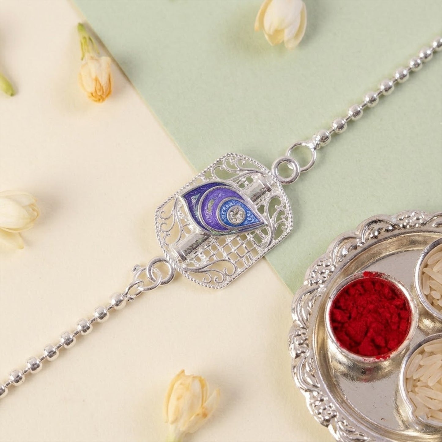 Close-up of silver peacock enamel charm on Rakhi for brother