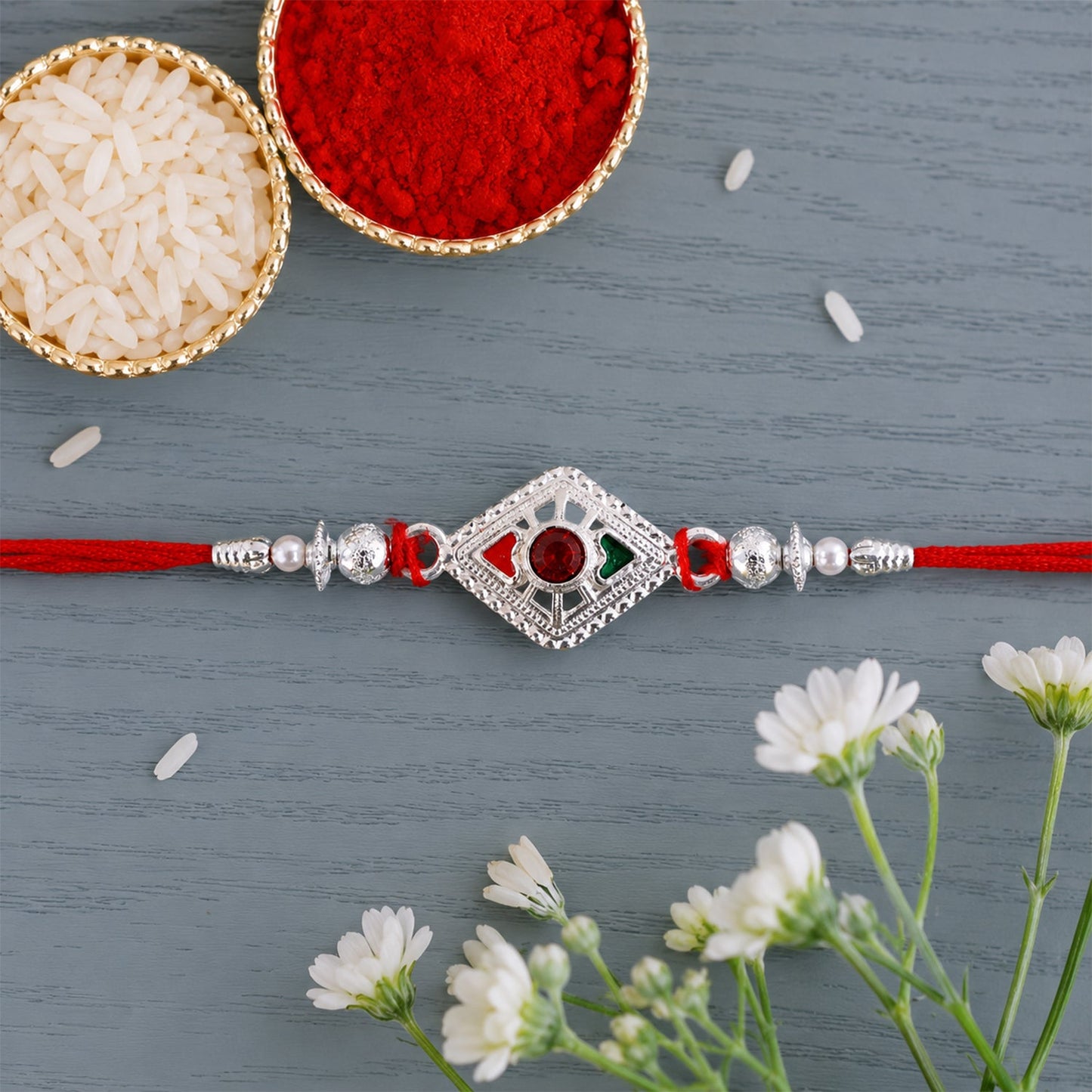 Close-up of silver rakhi featuring red stone and pearl beads