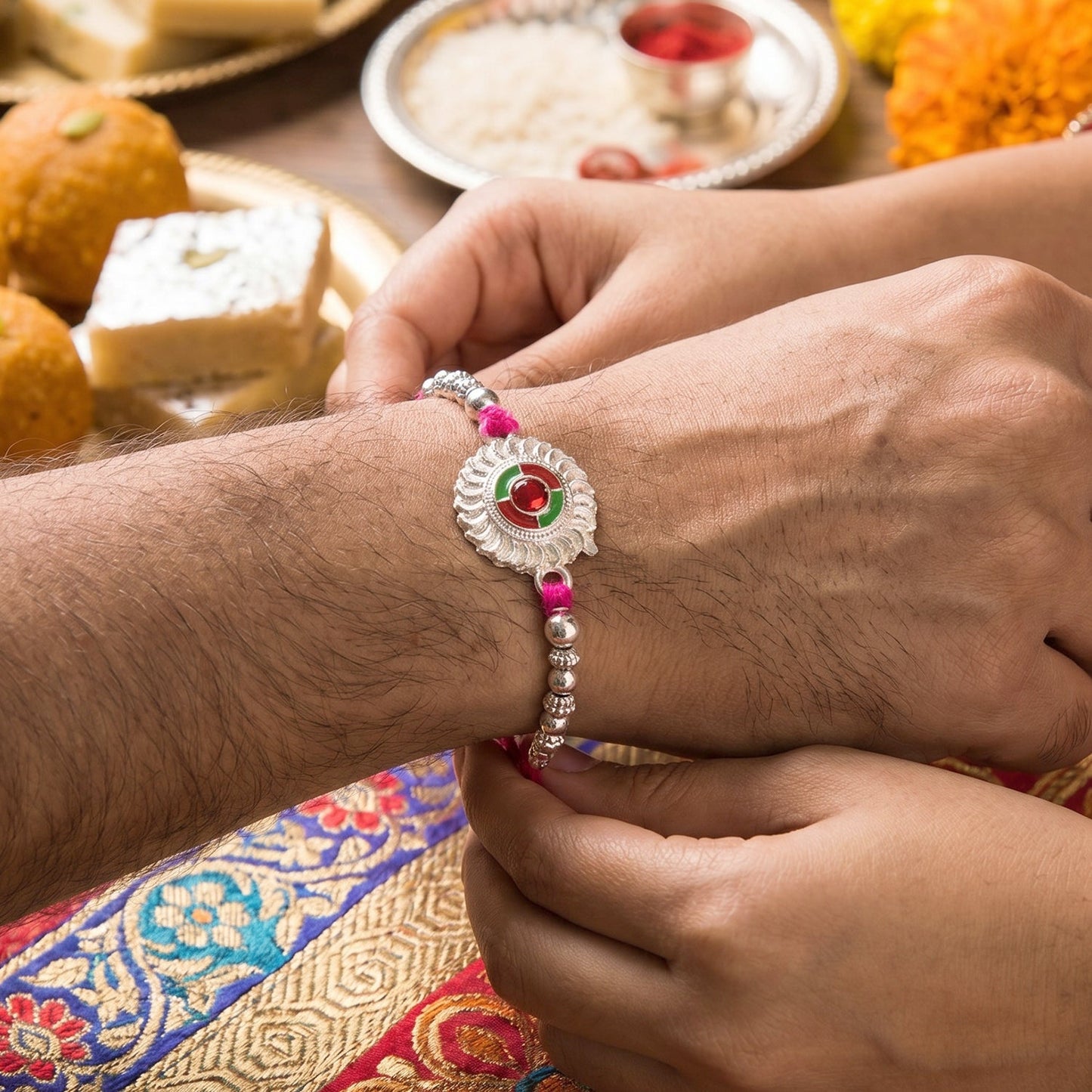 Side angle of traditional silver rakhi with floral design