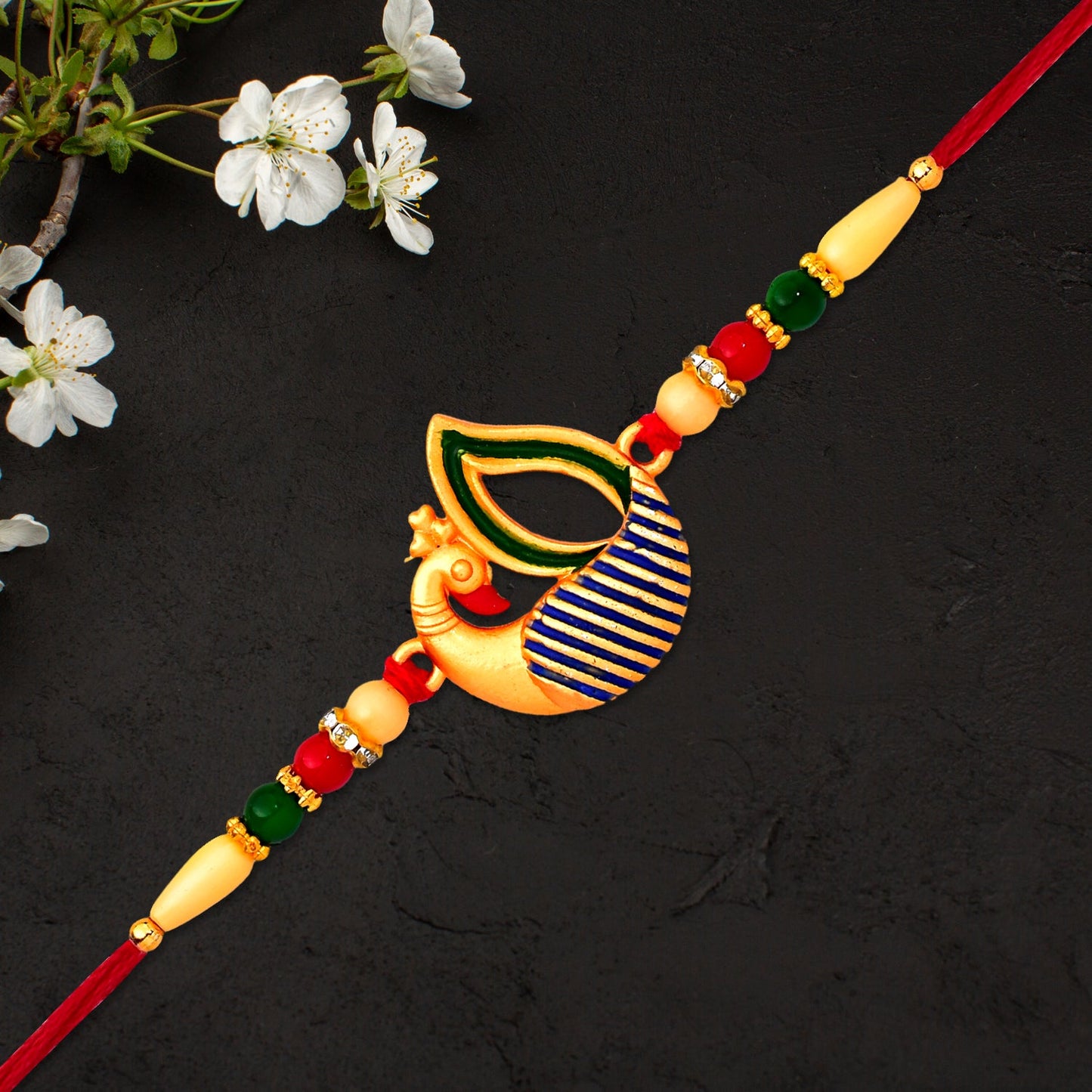 Designer Peacock Feather Rakhi laid on textured surface emphasizing colorful feather detail.