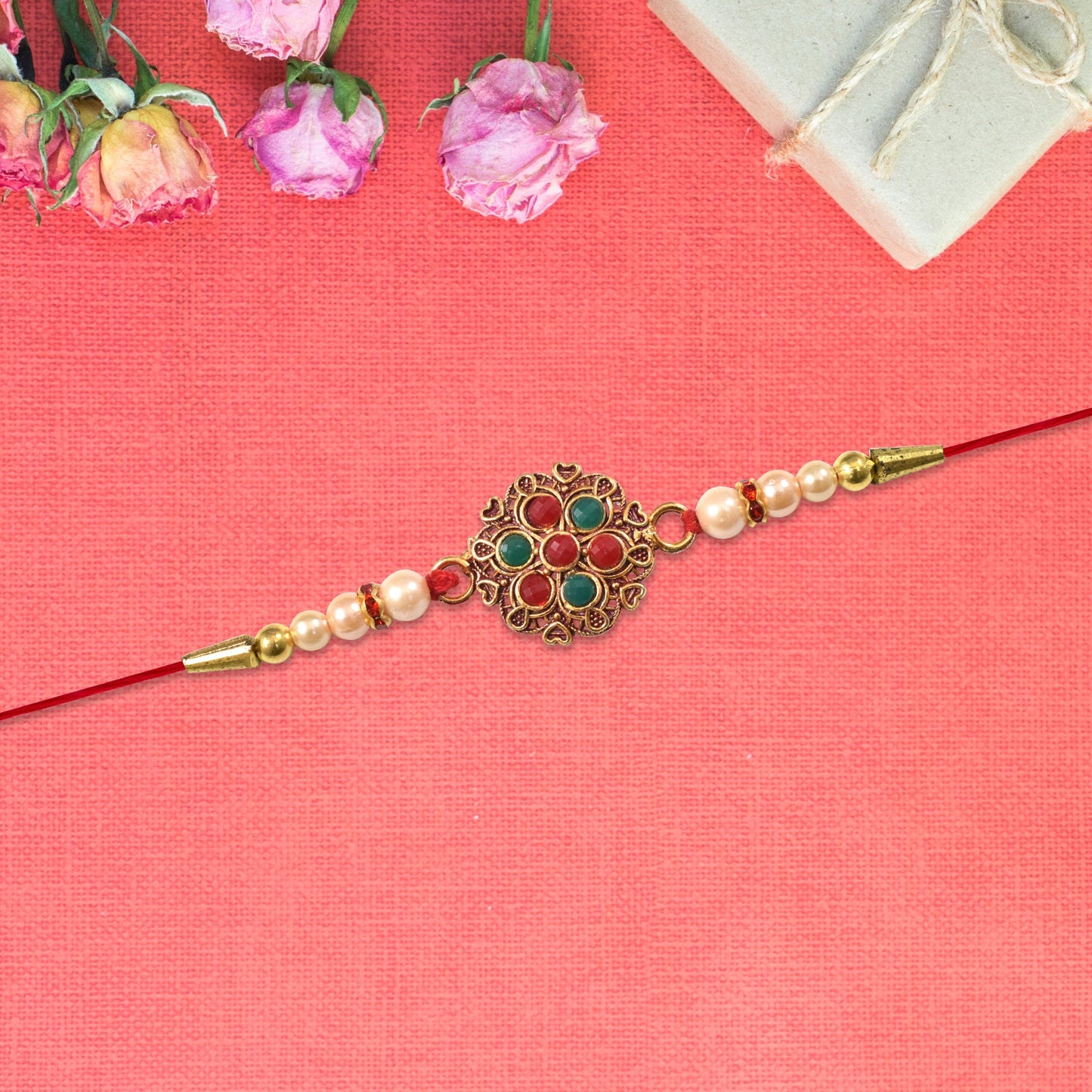 Close-up of designer Rakhi showcasing intricate beaded work and floral meenakari centerpiece