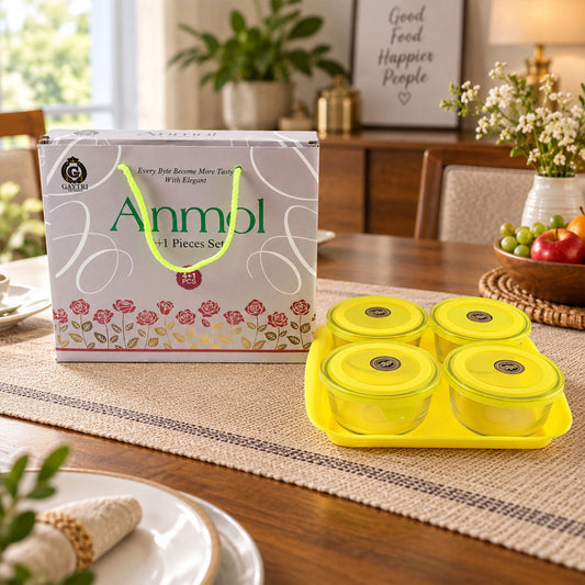 Four clear glass bowls with bright yellow lids on a matching yellow tray, beside a gift box.