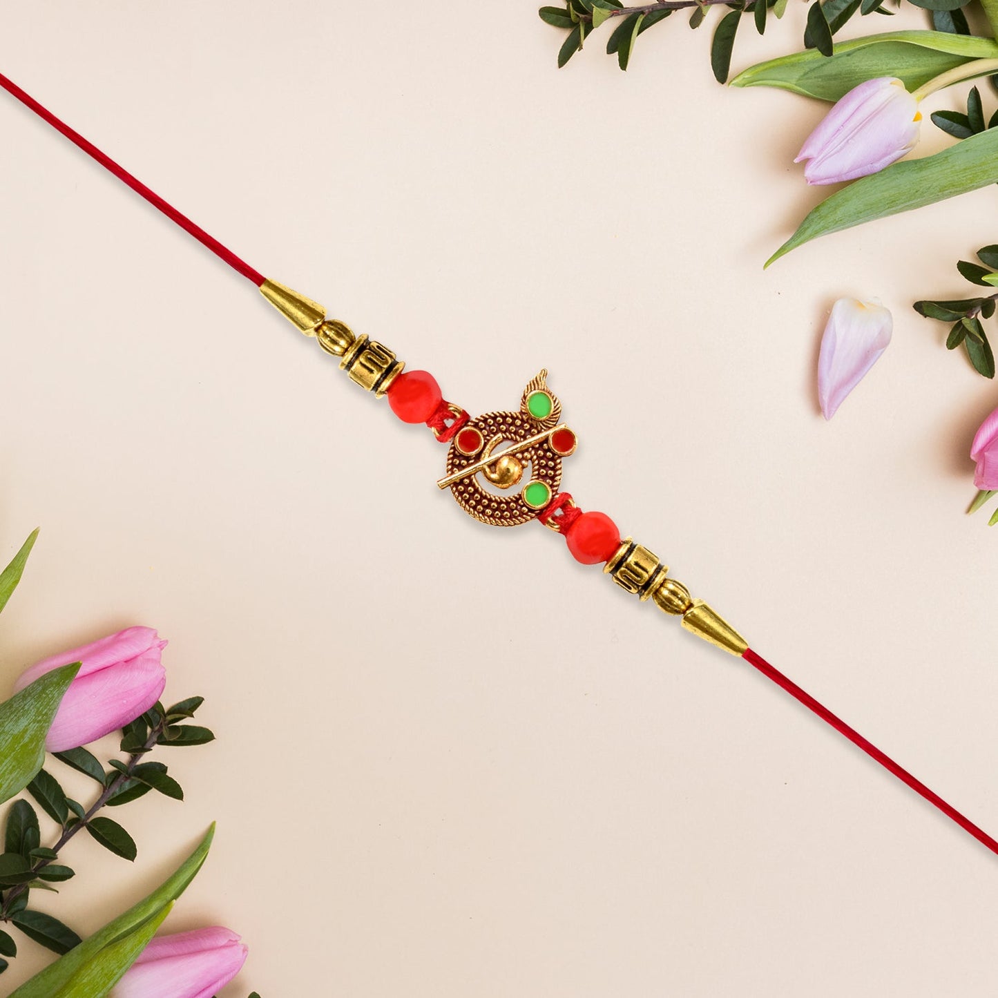 Beautiful red Krishna Rakhi placed among traditional Rakshabandhan elements.