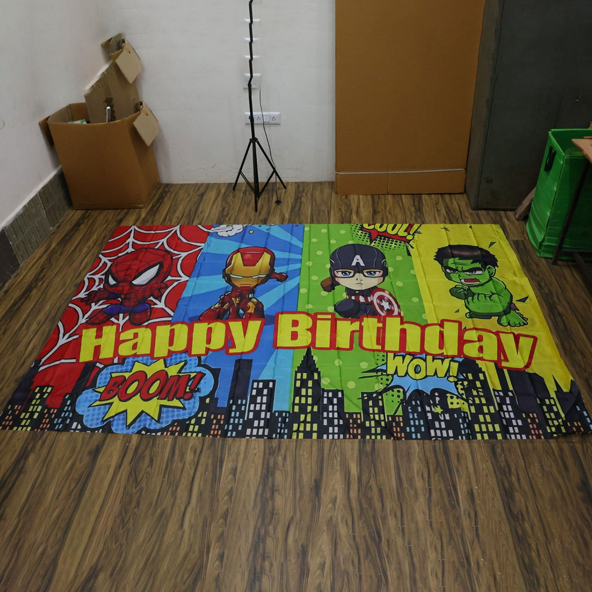 Actual cartoon superhero Happy Birthday backdrop laid flat on a wooden floor