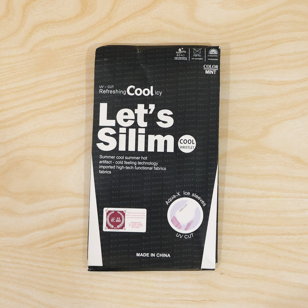 A black and white retail package for "Let's Silim Cool Icy" UV-cut arm sleeves, on a wooden surface.