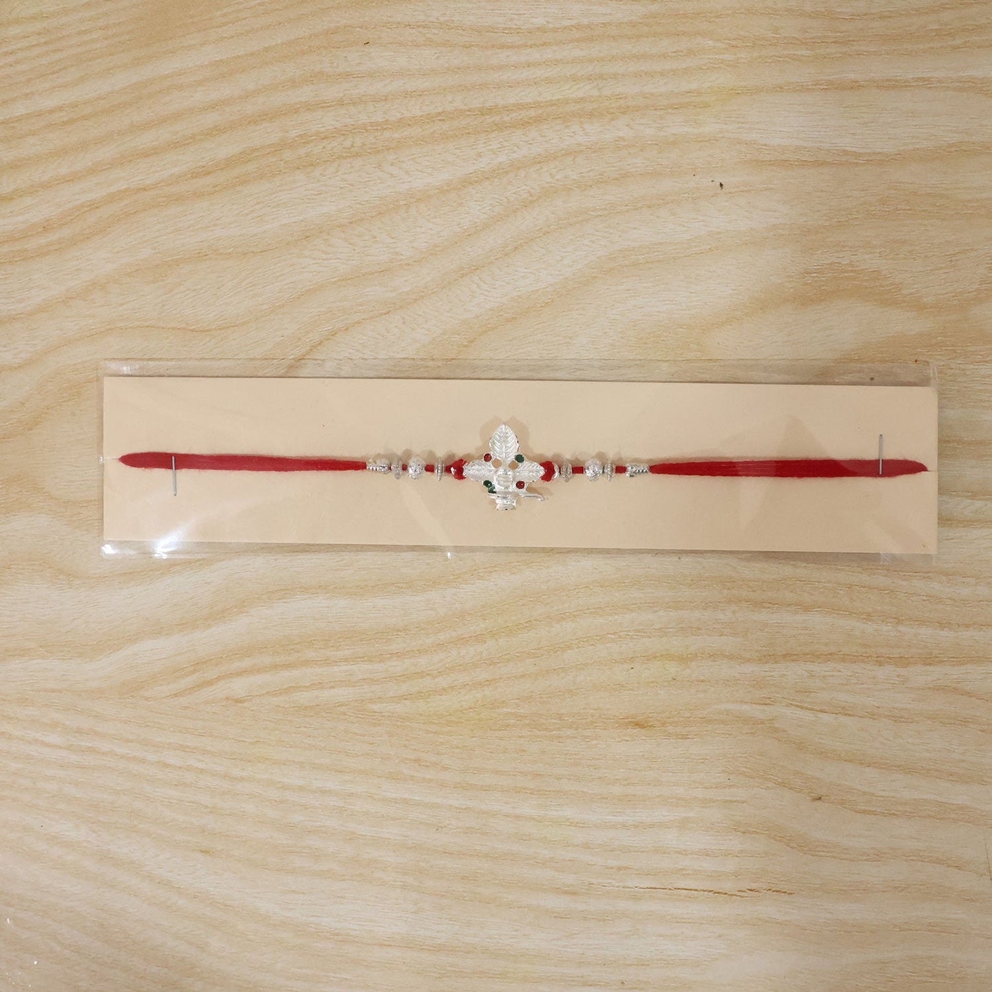 Silver Shivling leaf Rakhi on red thread isolated