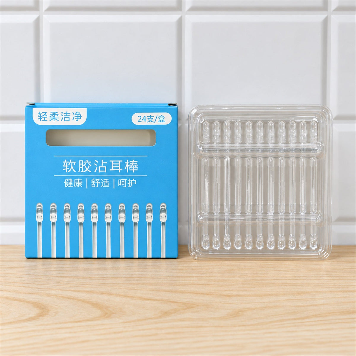 A blue box with Chinese text and a clear plastic holder with 24 ear cleaning sticks on a light wooden surface.