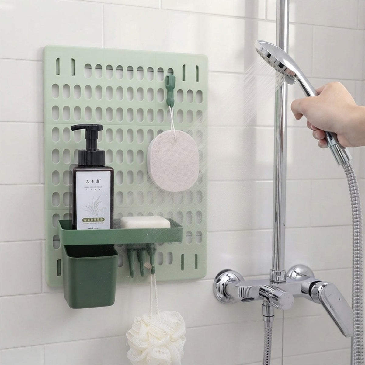 A light green pegboard with a dark green shelf holding soap and lotion, a dark green cup, and hooks holding a loofah, in a