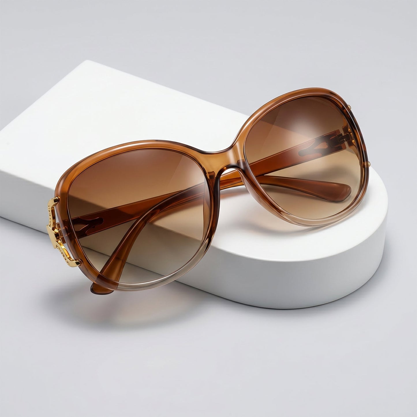 Close-up of the gradient tinted lenses and gold floral accent on oversized sunglasses.