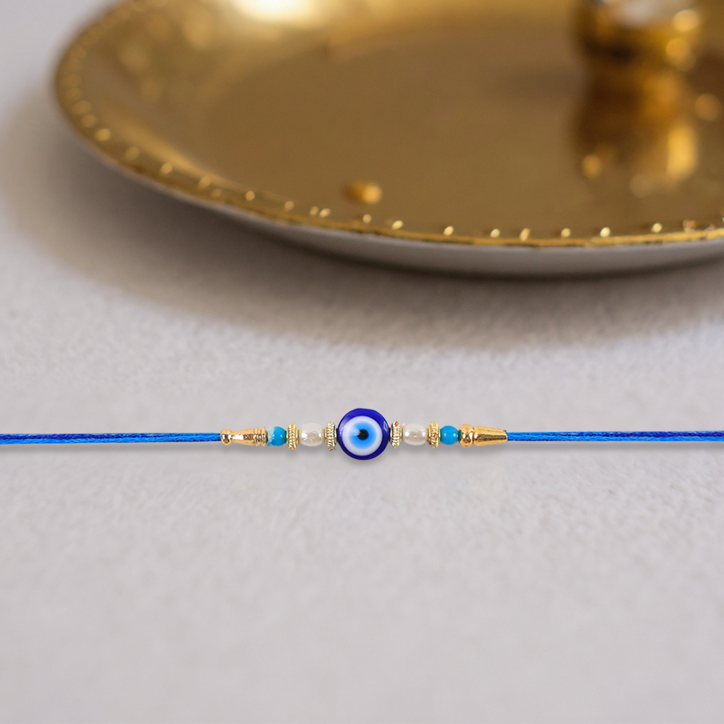 Close-up of a handcrafted Blue Rakhi with detailed pearl beads and golden accents