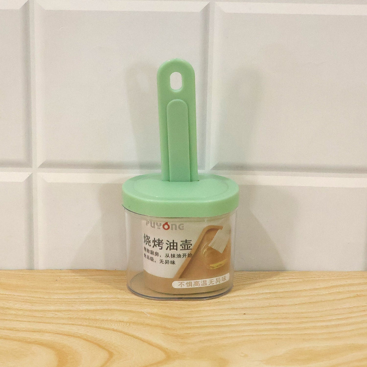 A green silicone brush stored in a clear container with a green lid, featuring a label with Chinese characters, against a