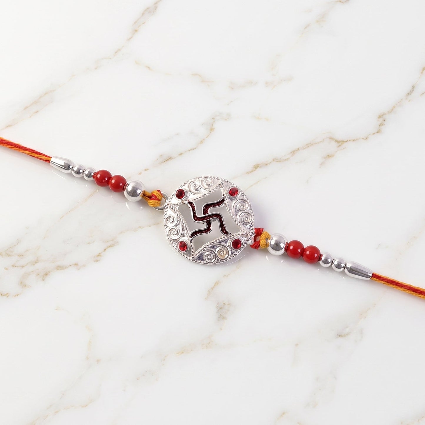 Elegant rakhi with silver swastik and beads on red thread