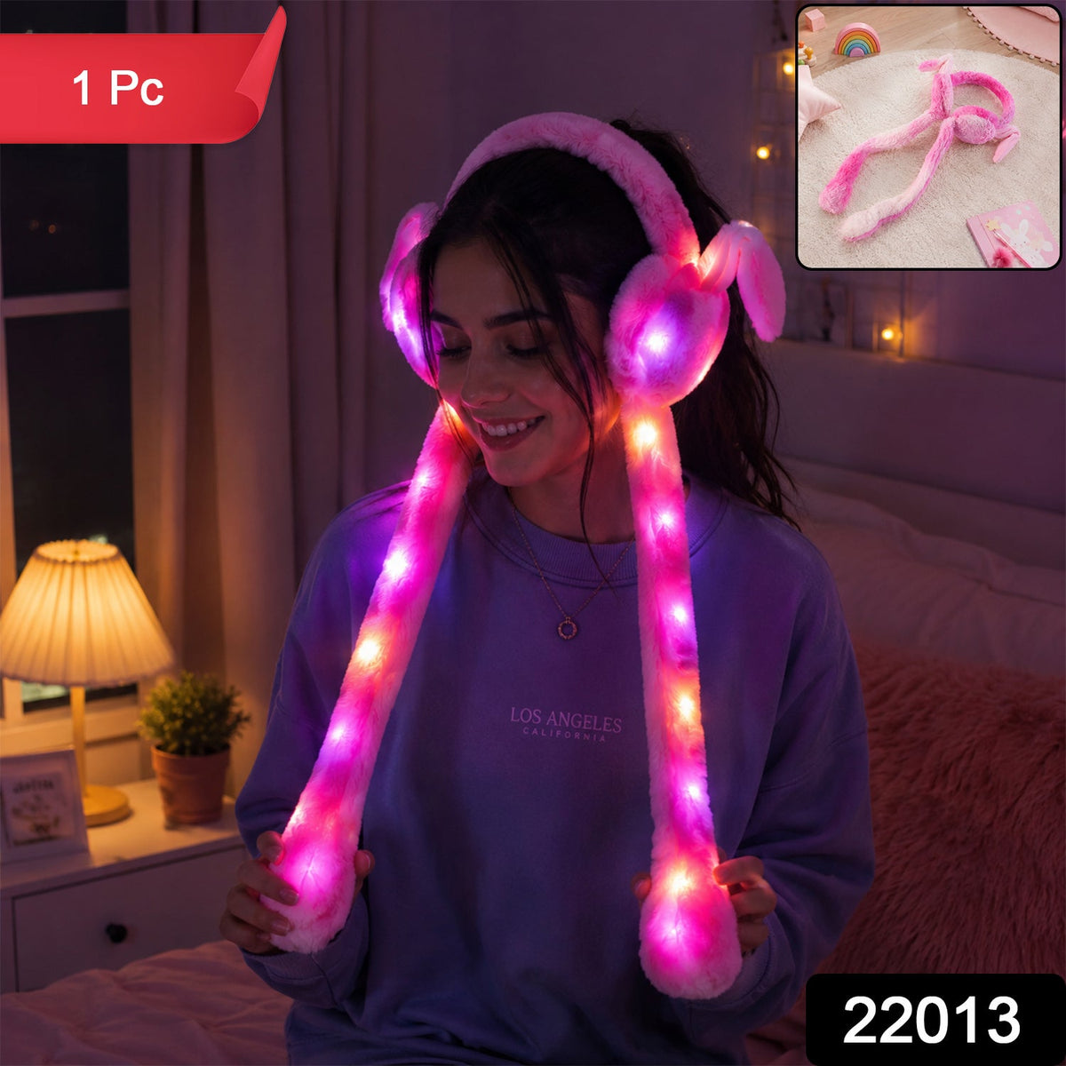 A young woman smiling while wearing pink LED light-up plush bunny earmuffs with long tails that glow brightly in a dimly lit