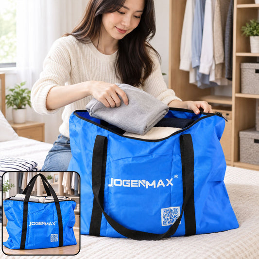 A woman places a folded grey blanket into a large blue JOGENMAX storage bag with black handles on a bed.