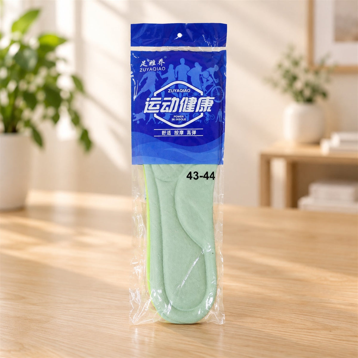 A pair of light green shoe insoles packaged in a clear plastic bag with blue and white Chinese text, on a wooden table.