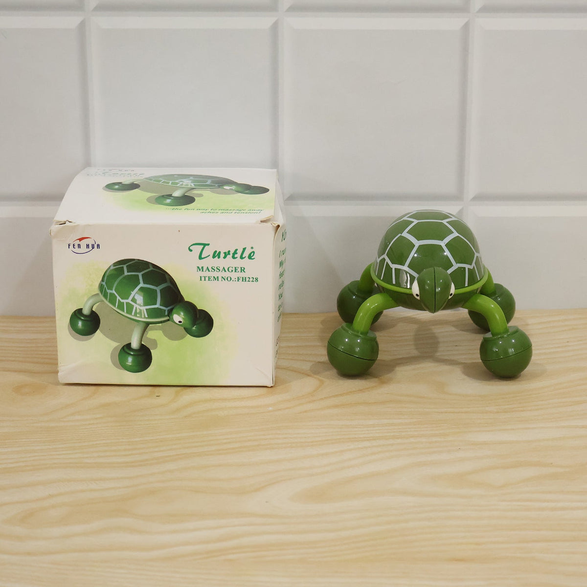 Green plastic turtle shape body massager shown with its retail packaging