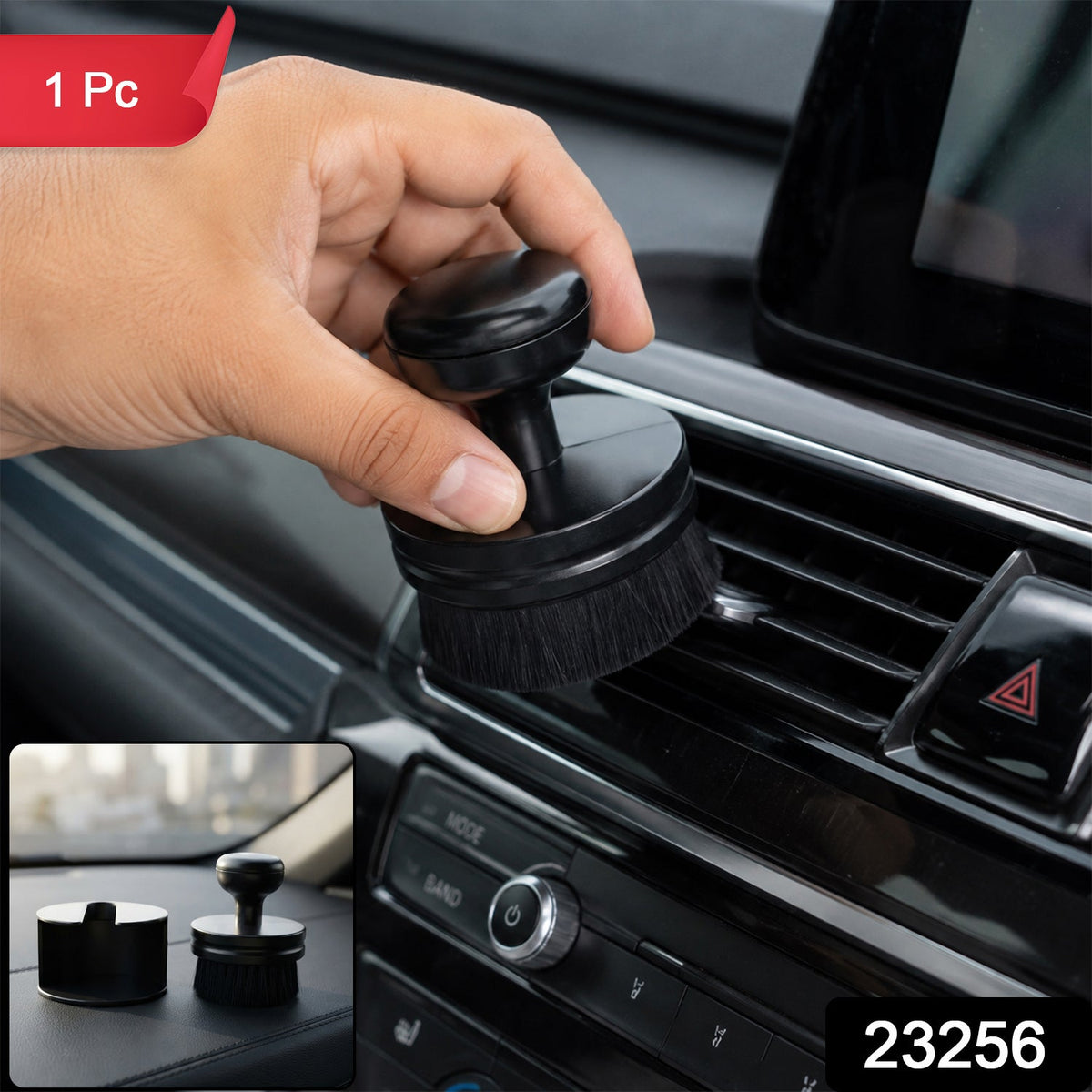 A hand holds a black detailing brush, cleaning a car's air vent, with a small inset showing the brush and its base â€“ view 2