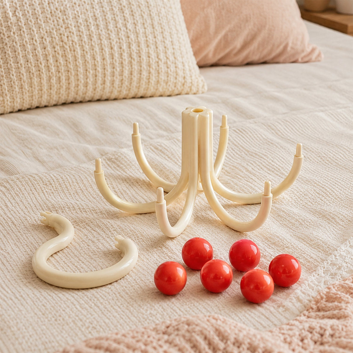 The disassembled cream multi-hook hanger parts, including the S-hook, base, and six red balls, are laid out on a beige