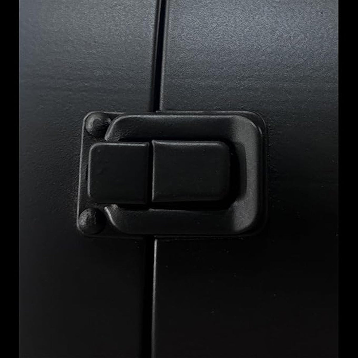 A close-up shot of the black metal latch mechanism on the side of the double-sided clock, showing its textured surface and