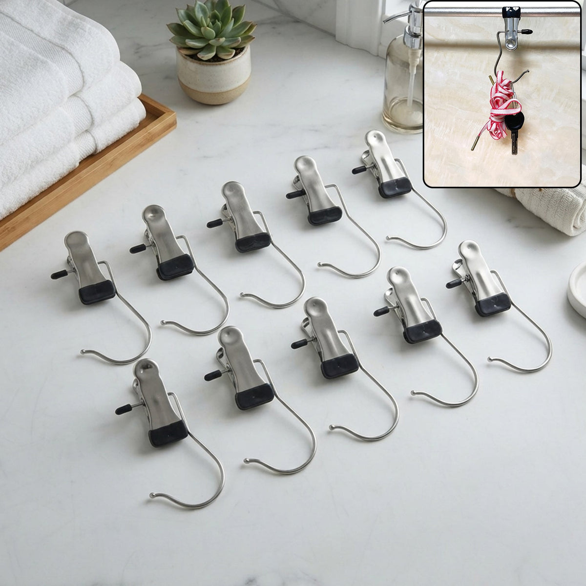 Ten metal clip hangers with black rubber tips are neatly arranged on a white marble countertop next to folded towels