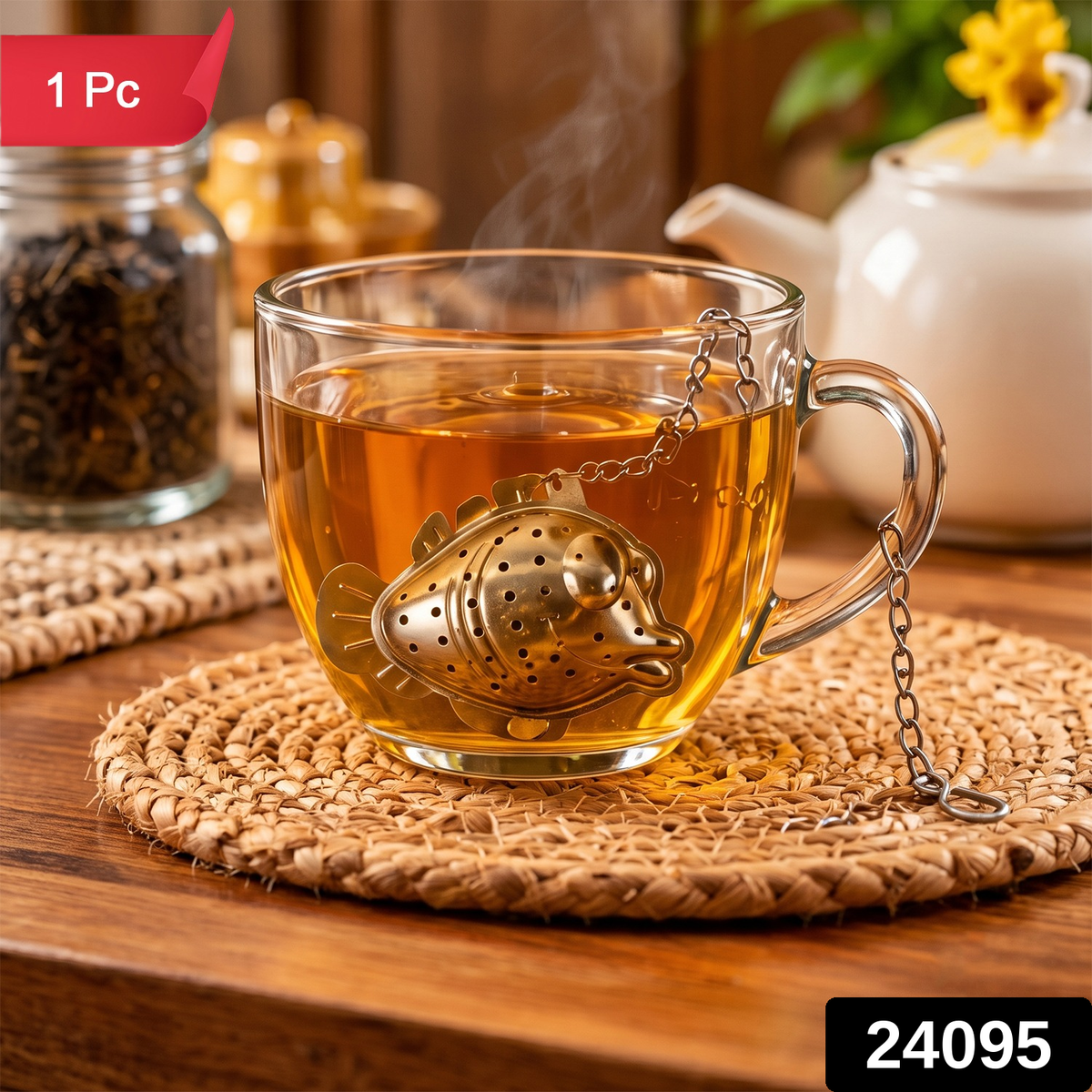 A fish-shaped tea infuser, made of shiny silver metal, hangs in a clear mug of hot tea on a wooden table.