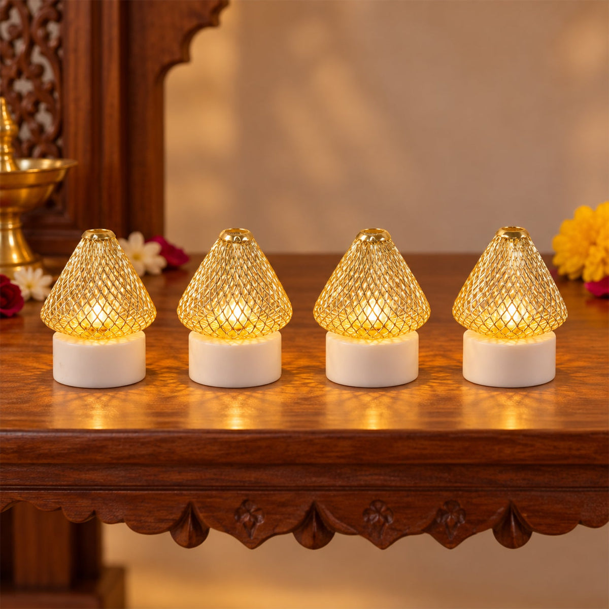 Four golden mesh LED lights with white bases illuminate a wooden table with festive flowers and a brass pot.