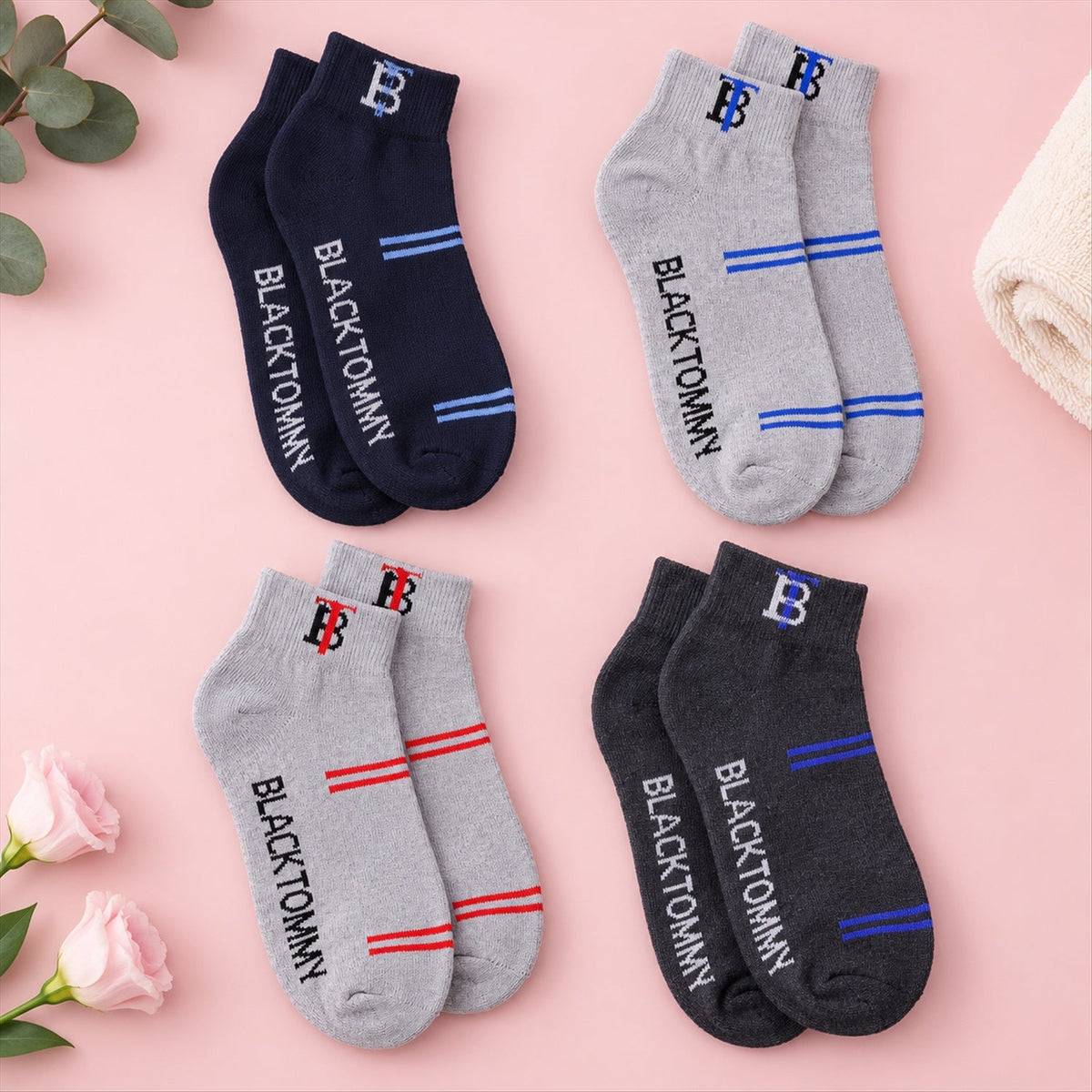 Four pairs of ankle socks in navy, grey, and charcoal, each with unique stripe and text colors, on a pink surface.