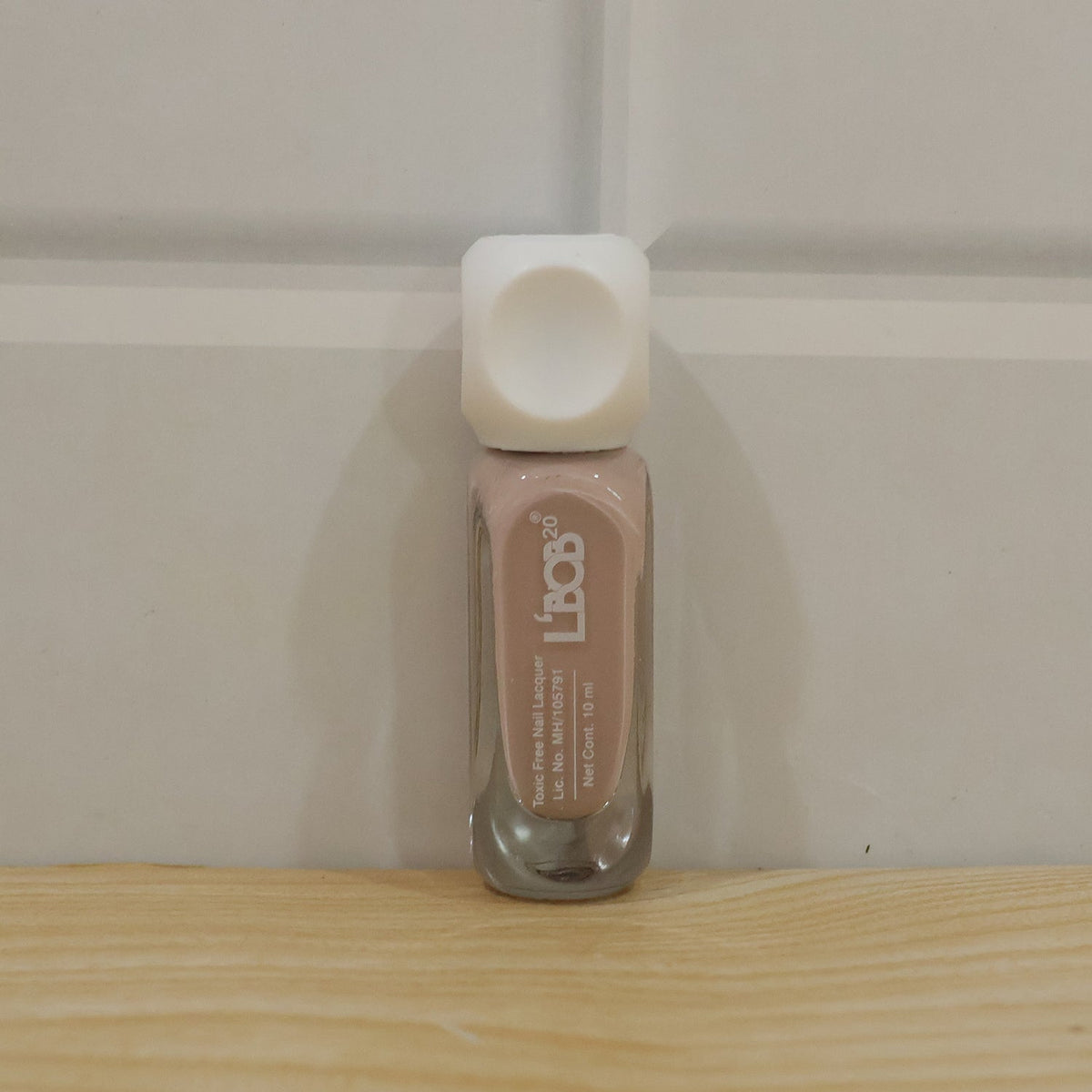Woman's hand applying nude pink nail lacquer