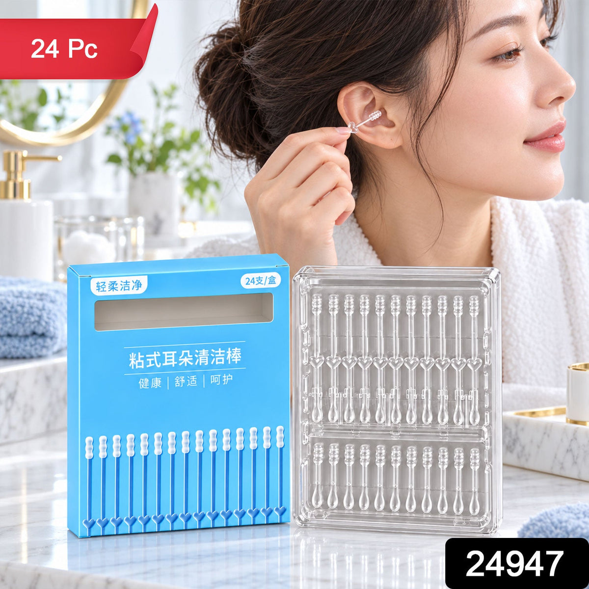 A woman in a white robe uses a clear silicone ear cleaner, with a blue box and clear case of 24 sticks on a counter. â€“ view 6