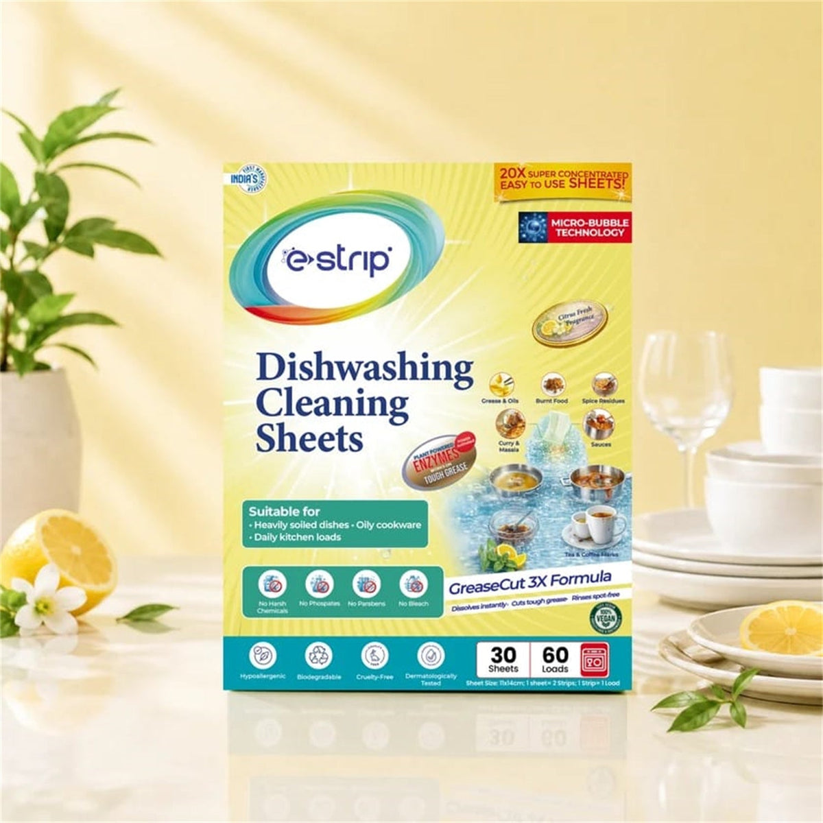 A box of e-strip dishwashing cleaning sheets on a counter with lemons, white flowers, and dishware.
