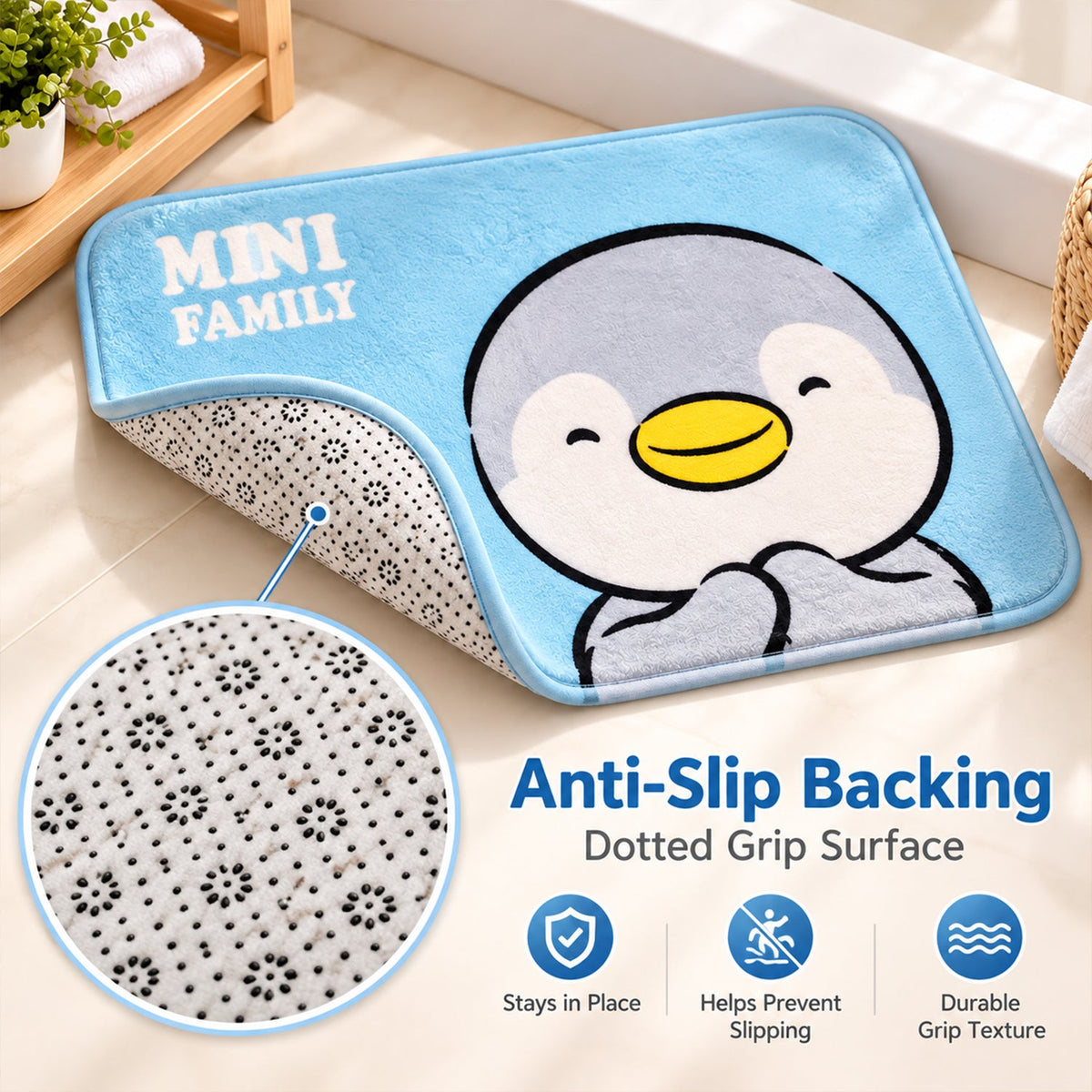 A light blue bath mat with a penguin design is partially lifted to reveal its anti-slip dotted grip surface.