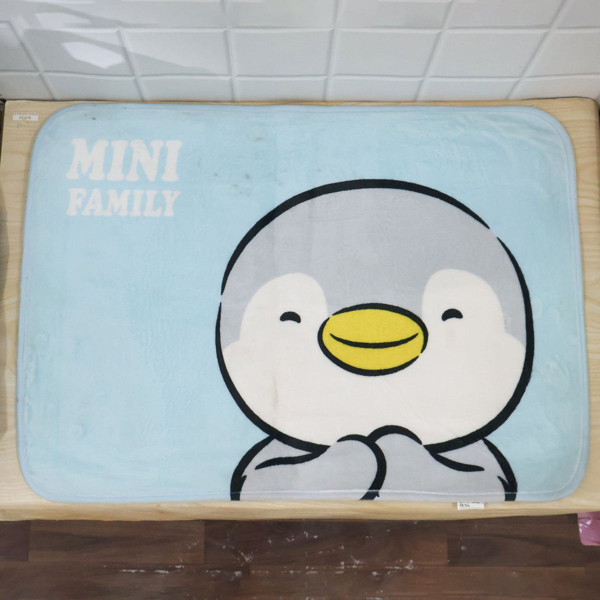 Rectangular cartoon penguin bath mat placed in a bathroom