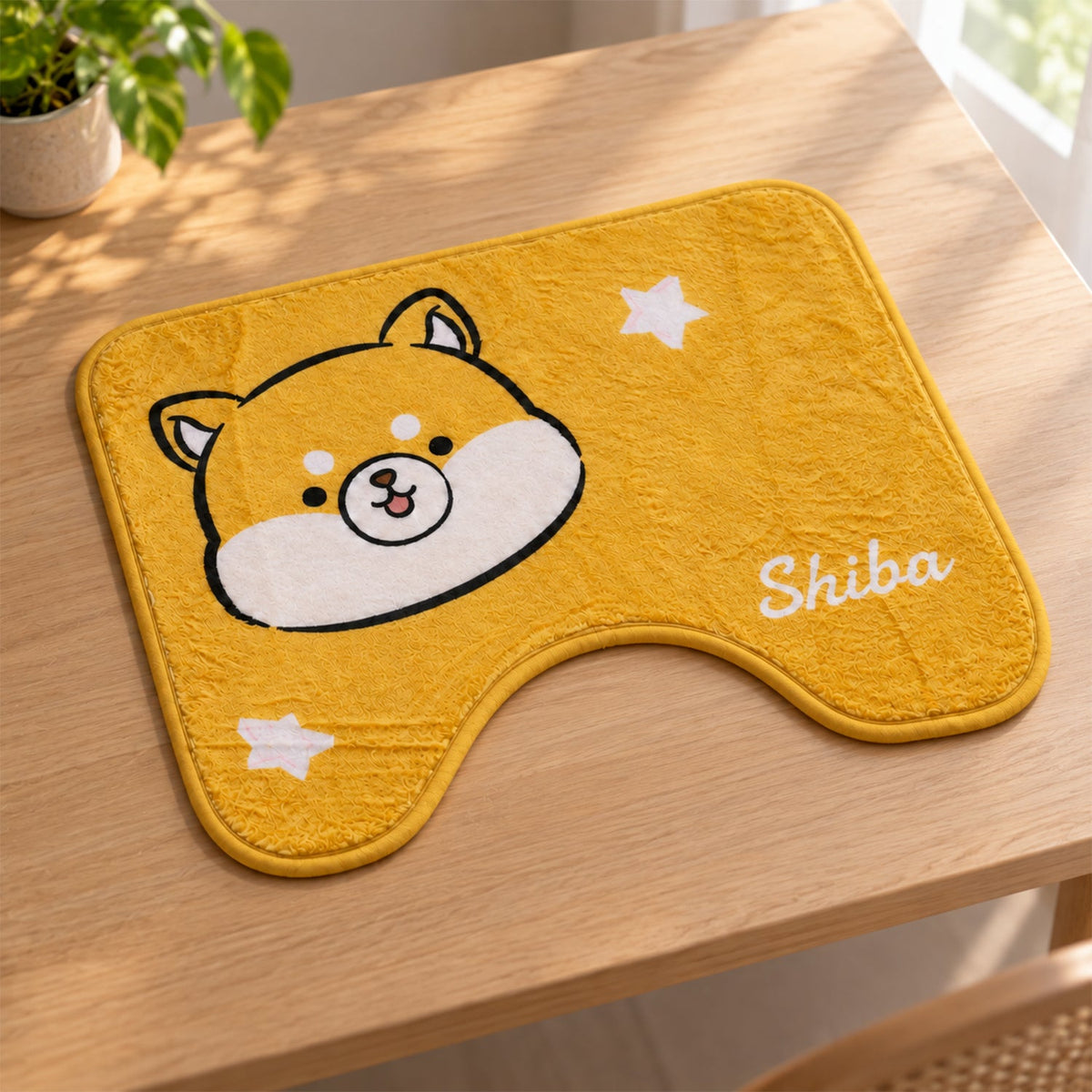 A yellow U-shaped toilet mat with a Shiba Inu design and white stars, resting on a light brown wooden surface.