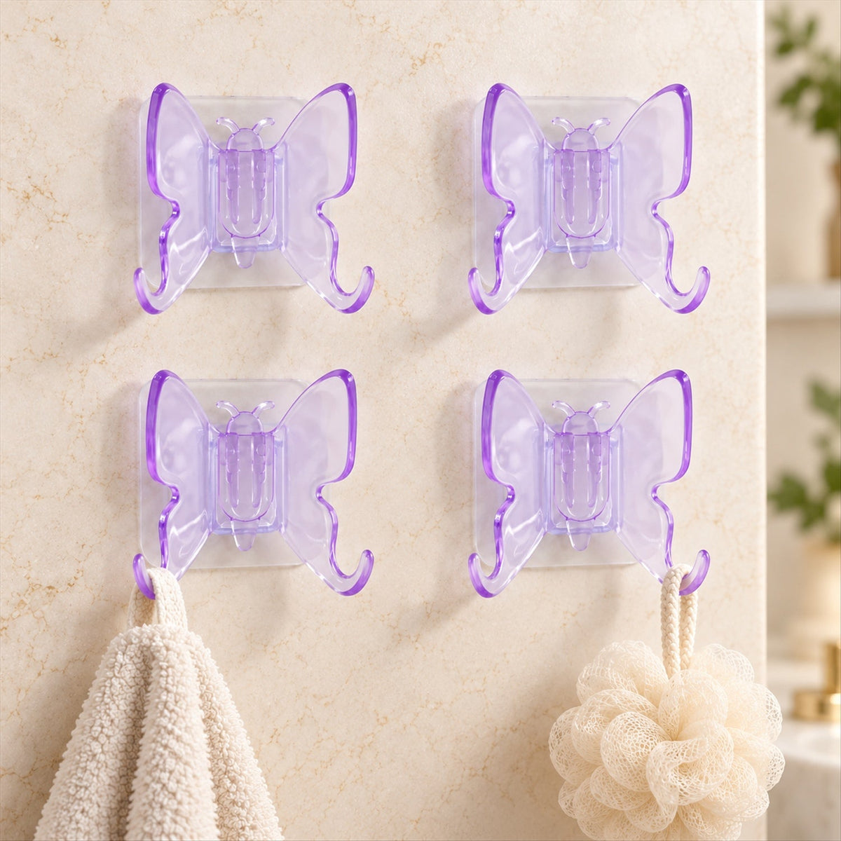 Four translucent purple butterfly-shaped wall hooks with double prongs, two holding a white towel and a beige bath pouf.