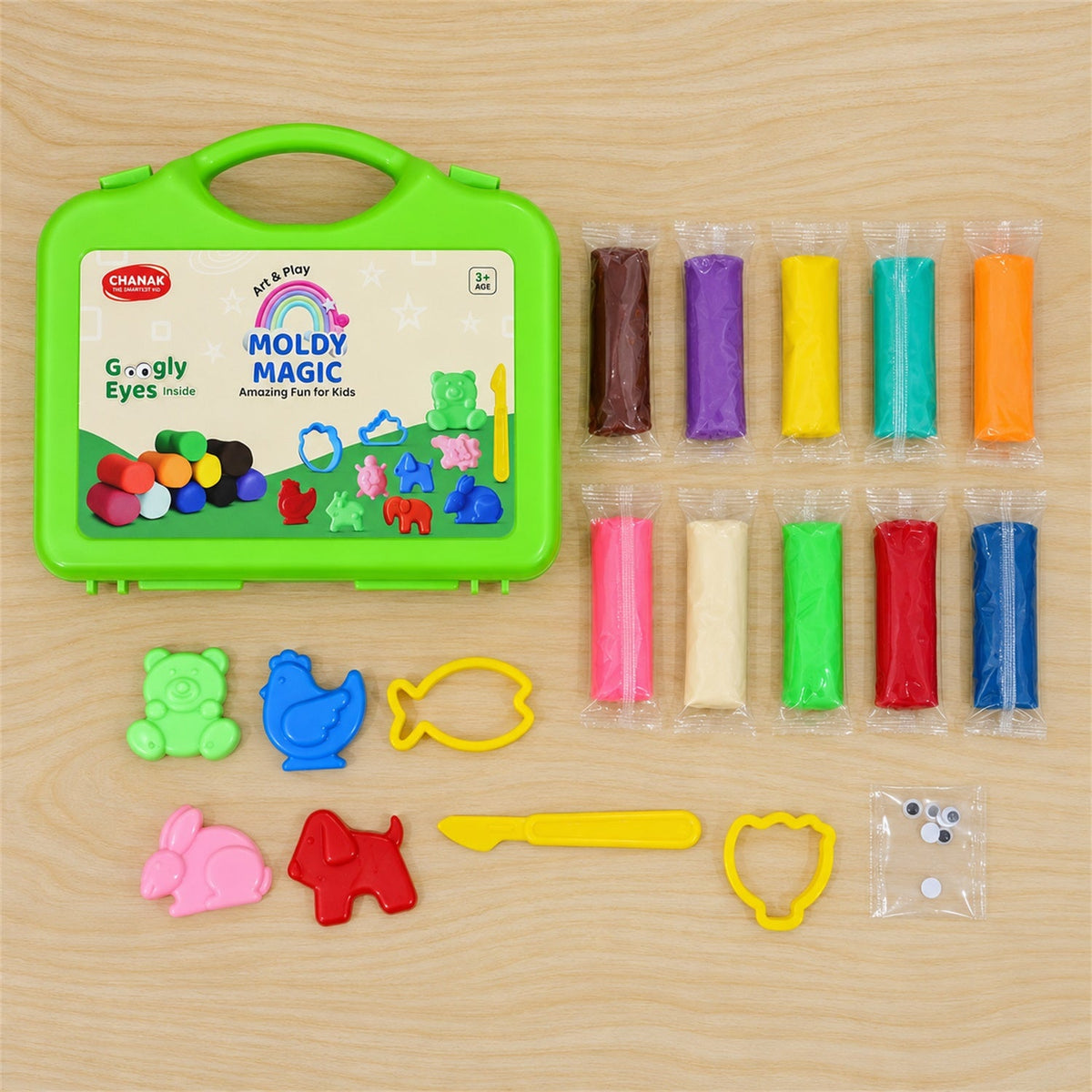 A green case, ten colorful clay packs, six plastic moulds, a yellow tool, and googly eyes are neatly arranged on wood.