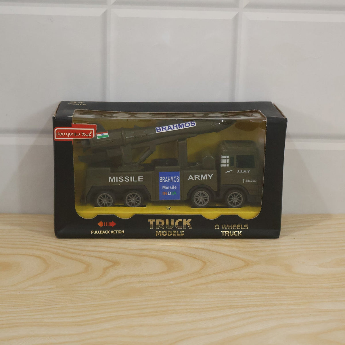 The green toy army truck with a missile launcher is displayed in its black and clear plastic packaging.