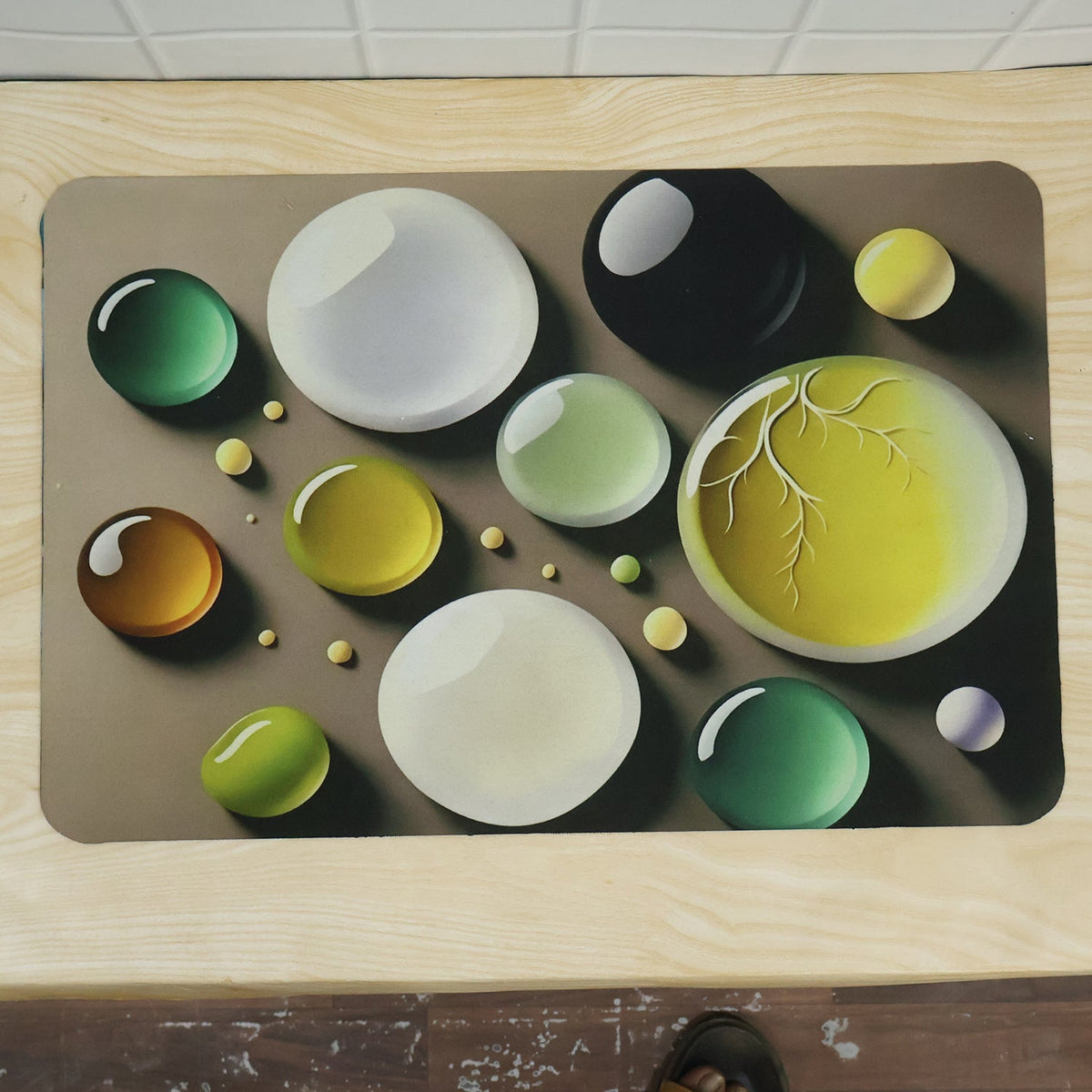 A brown rectangular mat with a colorful bubble print, featuring various sizes of green, yellow, white, and black bubbles.
