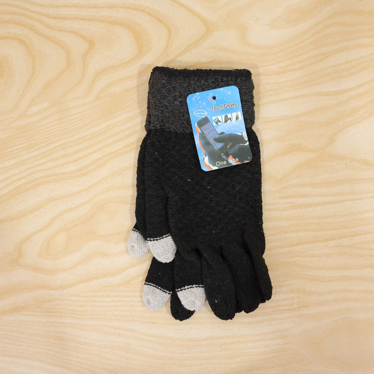 Folded pair of black knit gloves with gray cuffs and light gray fingertips, with a small product tag, on a wooden background.