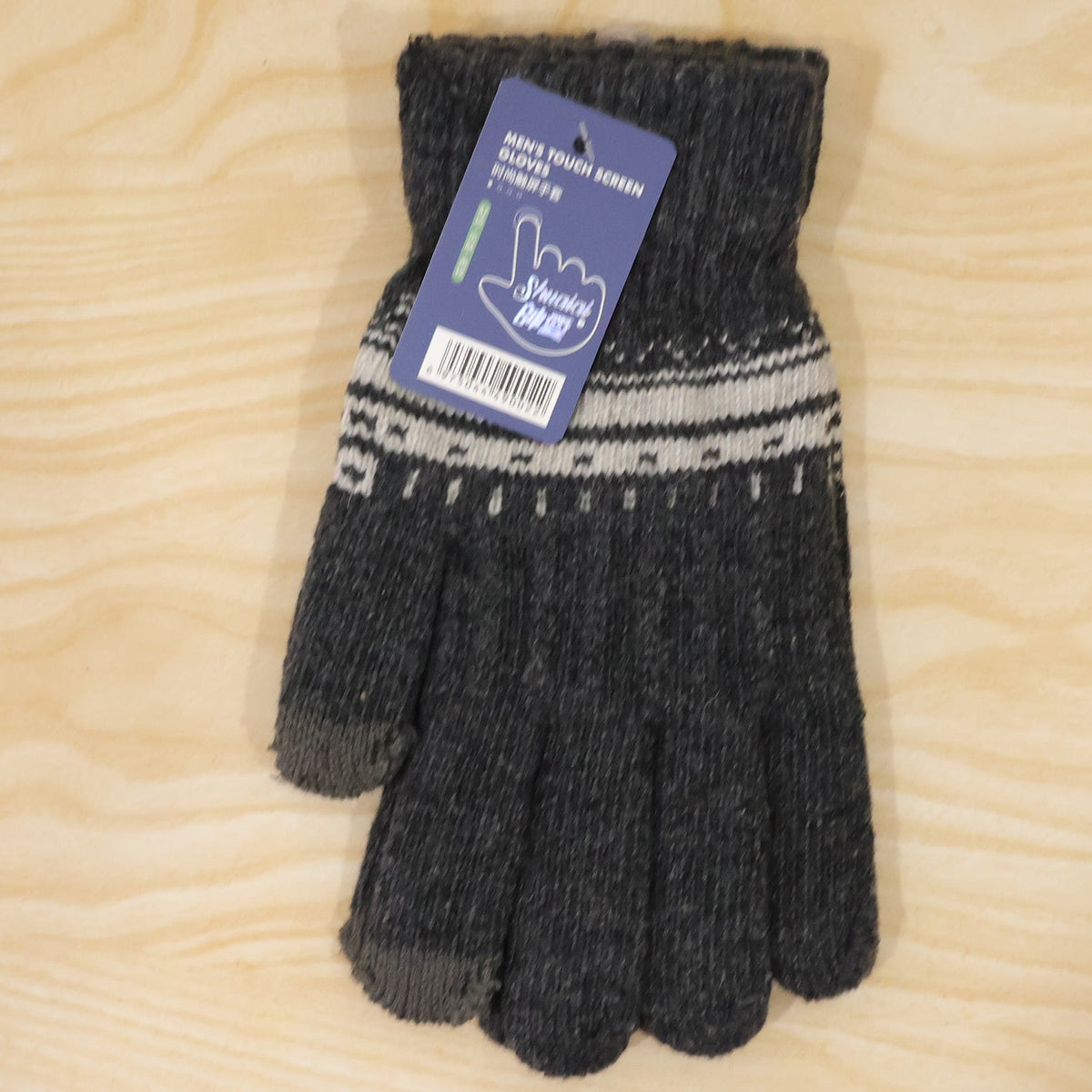 A single dark gray knitted glove with white patterned cuff and a product tag lies flat on a light wooden surface.