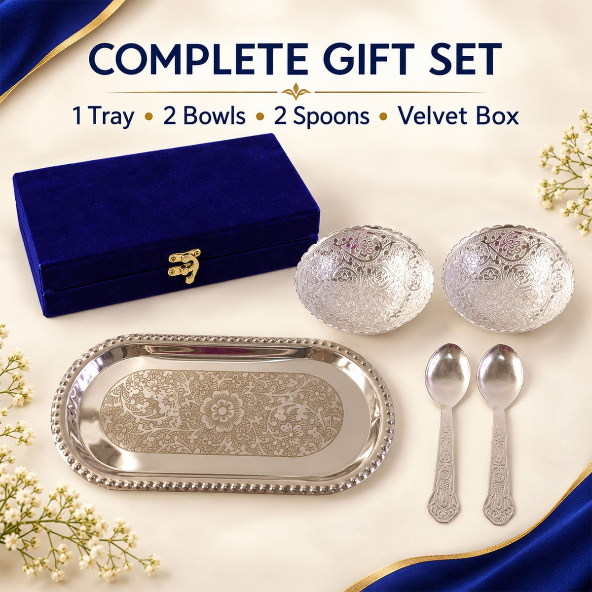 A complete silver-plated gift set with a tray, two bowls, two spoons, and a blue velvet box, surrounded by white flowers.