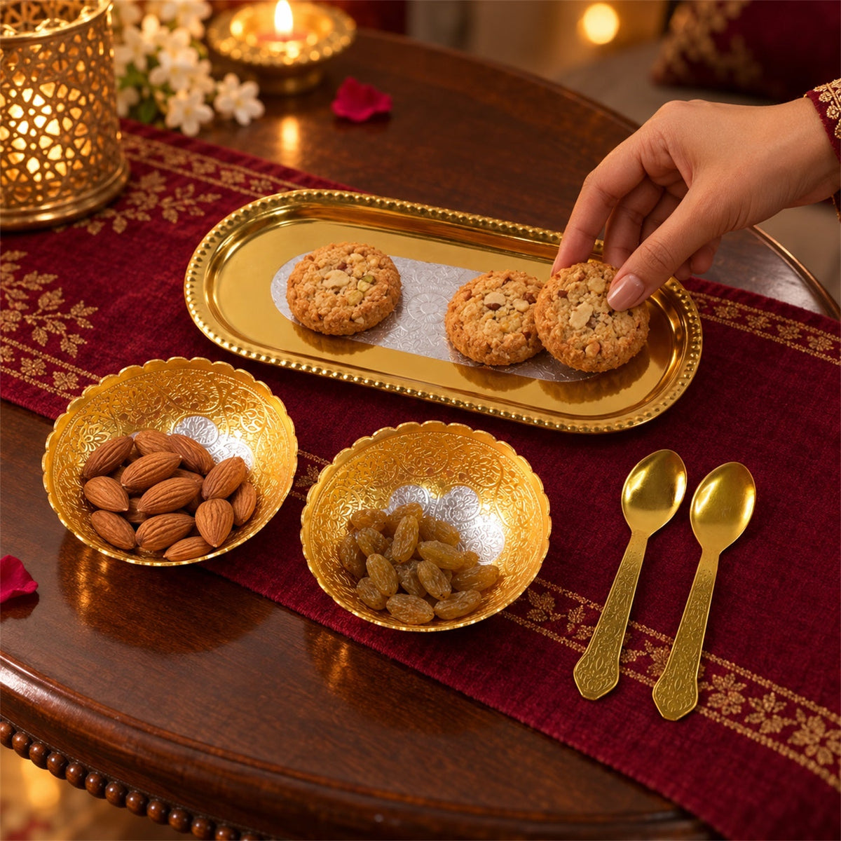 Two golden bowls with almonds and raisins, two golden spoons, and a hand reaching for cookies on a tray.