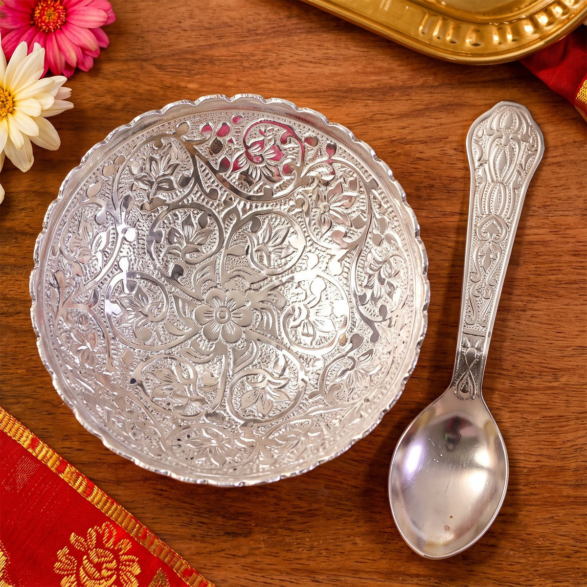 Overhead view of the silver finish floral serving bowl and matching spoon on a wooden surface.