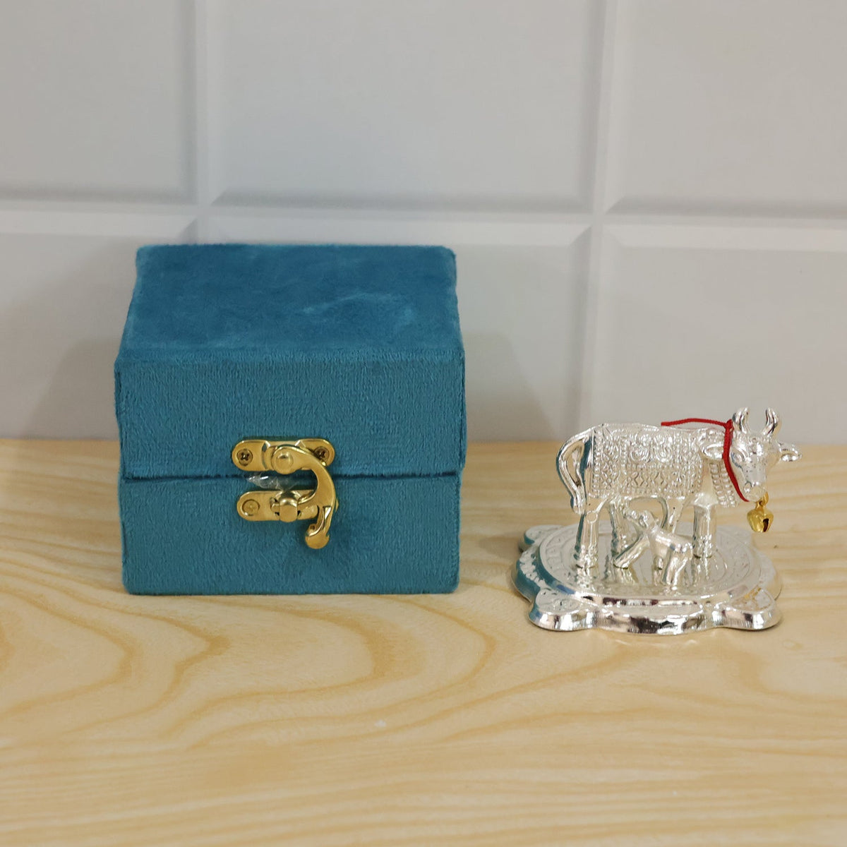 Silver Kamdhenu cow and calf idol used in a home puja decor setting