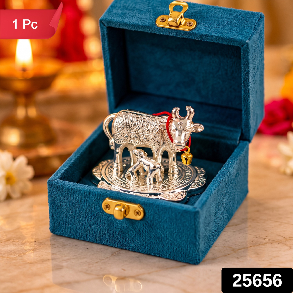 The silver cow and calf idol in the teal box, with a glowing lamp and flowers in the background.