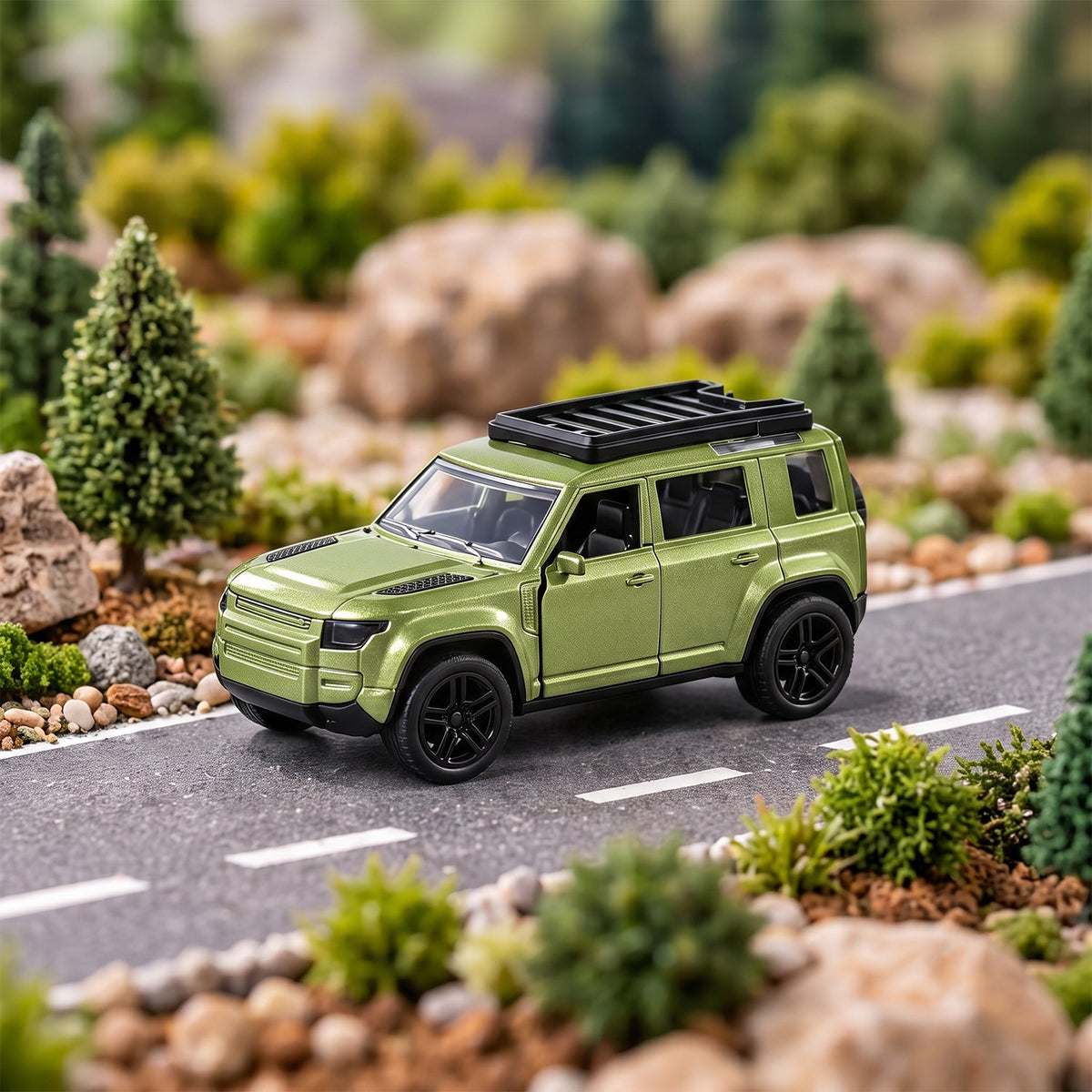 A metallic green die-cast SUV toy with a roof rack is parked on a miniature road surrounded by small trees and rocks.