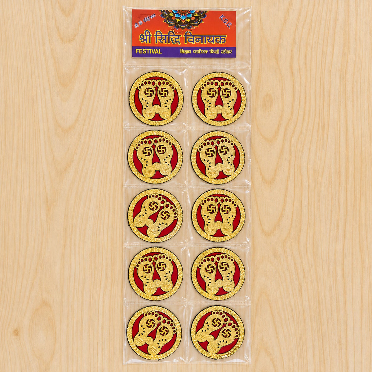 Ten golden Lakshmi Charan stickers with red backgrounds packaged in a clear plastic sleeve on a light wooden surface.