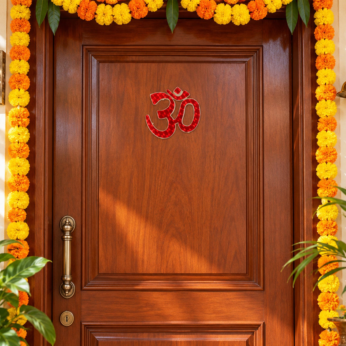 A red Om symbol sticker is centrally placed on a wooden door, flanked by long orange and yellow marigold garlands.