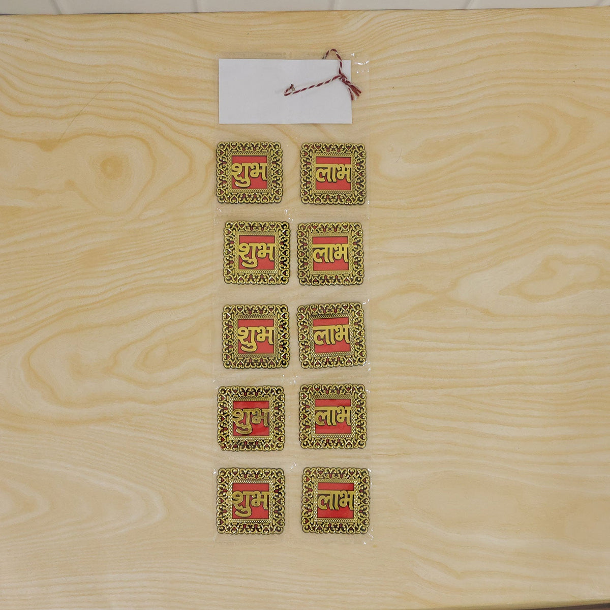 Ten individual Shubh Labh stickers, arranged in five pairs, sealed in plastic packaging on a light wooden surface.