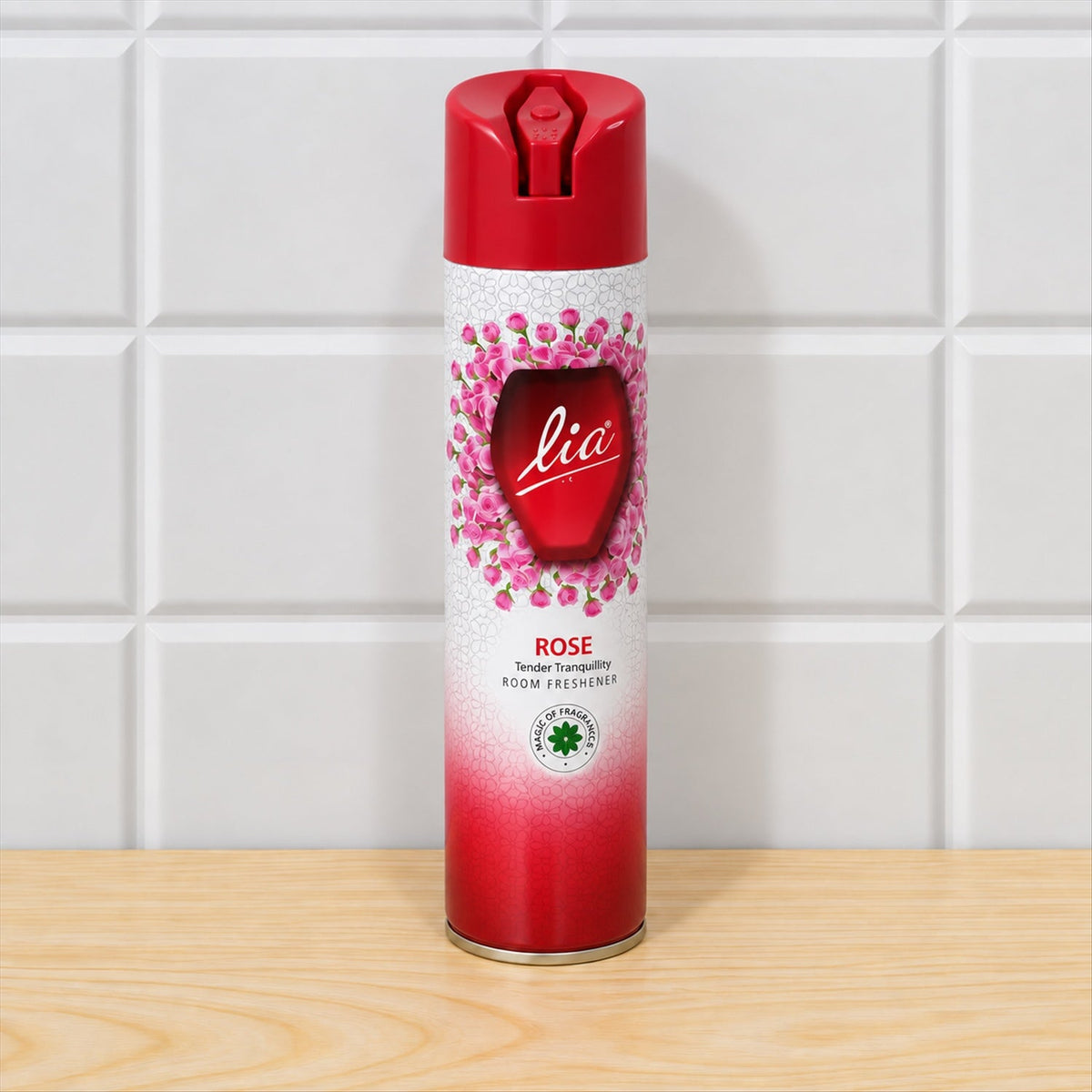 Red and white aerosol can with a pink rose pattern, standing upright on a light wooden surface against white tiled wall.