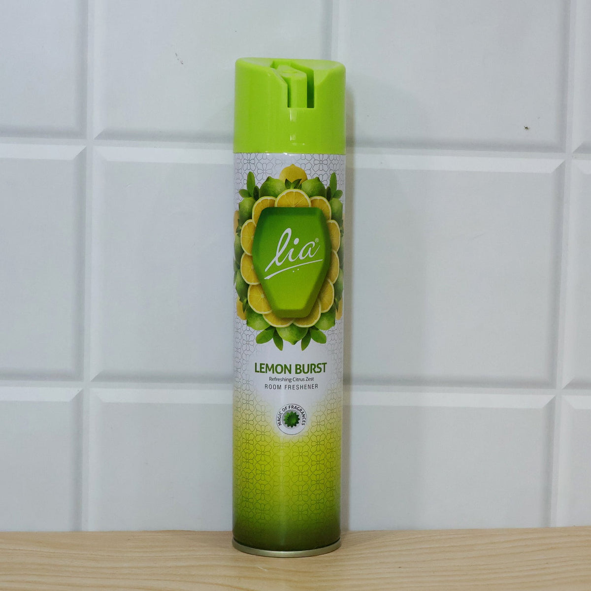 A Lia Lemon Burst room freshener bottle stands on a light wooden surface in front of a white tiled wall.